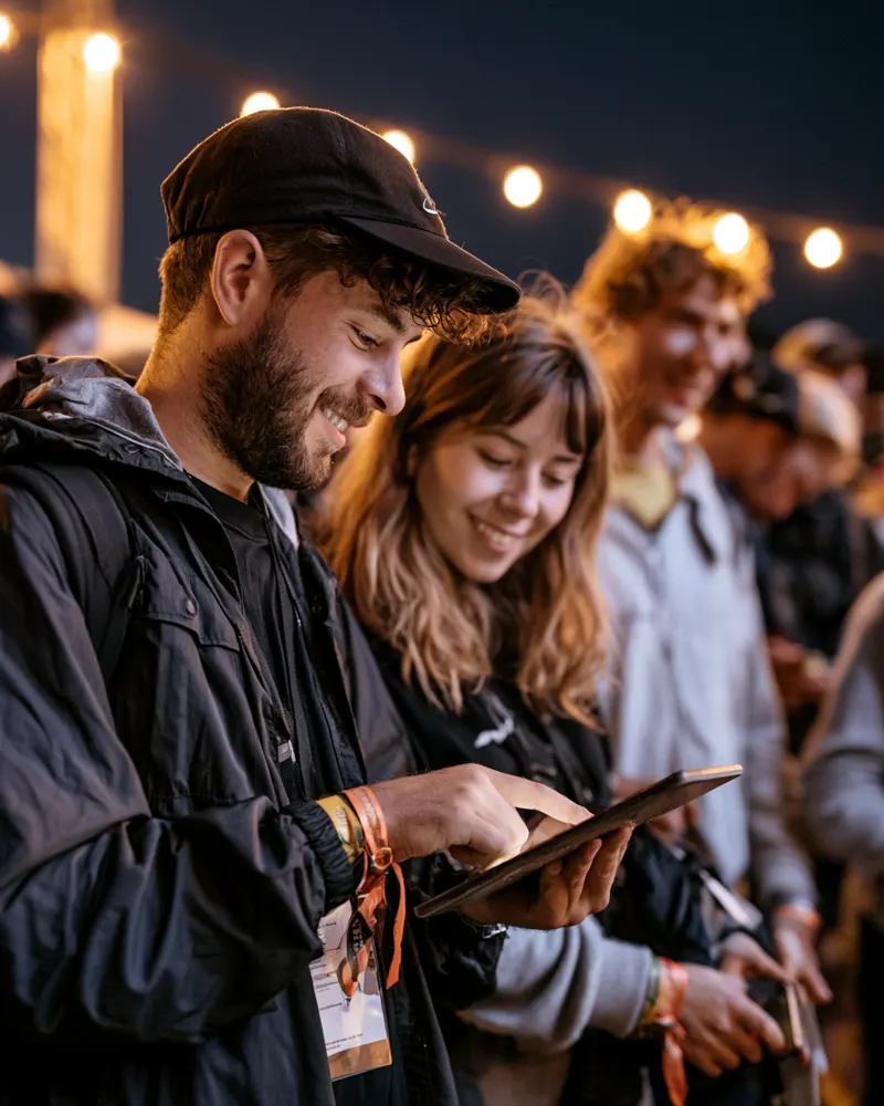 Staff member with a tablet greeting guests at an evening event
